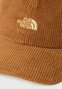 Καφέ καπέλο από κορδούρα με κεντημένο μπεζ λογότυπο "The North Face" στον μπροστινό πίνακα και ορατές ραφές στο γείσο.