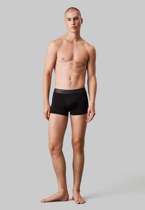 Bóxer ajustado negro con una cinturilla suave que lleva el logo de "Calvin Klein" en azul, fabricado con una tela lisa y elástica.