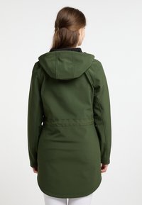 Veste verte à capuche avec une taille cintrée, des manches longues et un ourlet légèrement courbé. Fabriquée en matériau lisse et résistant. Sans fermetures visibles.