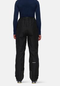 Pantalons de ski noirs imperméables avec une taille ajustable, des poignets renforcés et un tissu respirant. Comprend un logo réfléchissant sur le bas de la jambe.
