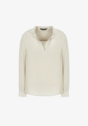 Blusa a maniche lunghe di un leggero beige, realizzata in tessuto morbido. Presenta un colletto e una leggera piega sul davanti, con un orlo arrotondato.