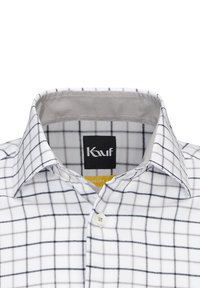 Camicia bianca con bottoni, con un motivo a griglia nera, dotata di un colletto classico e di un'etichetta interna con il nome del marchio. Materiale in misto cotone.
