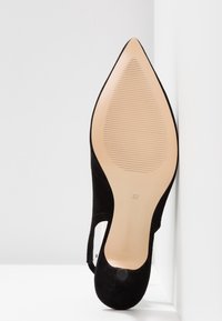 Chaussure à talon haut en daim noir avec un bout pointu, un design découpé, et une semelle beige lisse. Taille 37 estampillée sur la semelle intérieure.