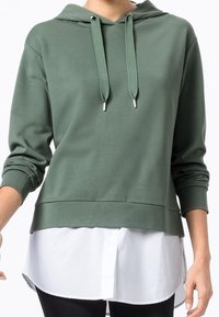 Zielona bluza z kapturem i długimi rękawami, wyposażona w sznurki i warstwowy, biały brzeg koszuli, wykonana z miękkiej tkaniny o gładkiej fakturze.