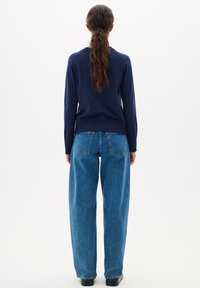 Marinblå stickad tröja med ribbade muddar, ihopkopplad med lösa, ljusblå denimjeans med hög midja, som har bakfickor och en rak passform.