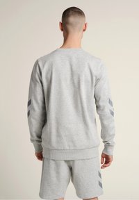 Szary sweatshirt z długimi rękawami, ściągaczami przy mankietach i okrągłym dekoltem. Posiada ciemnoszare ukośne paski na rękawach. Miękki materiał.