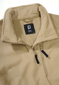 Barna polár pulóver félig cipzáros gallérral, texturált anyaggal, fekete cipzárfogókkal és a gallér belsejében található címkével.