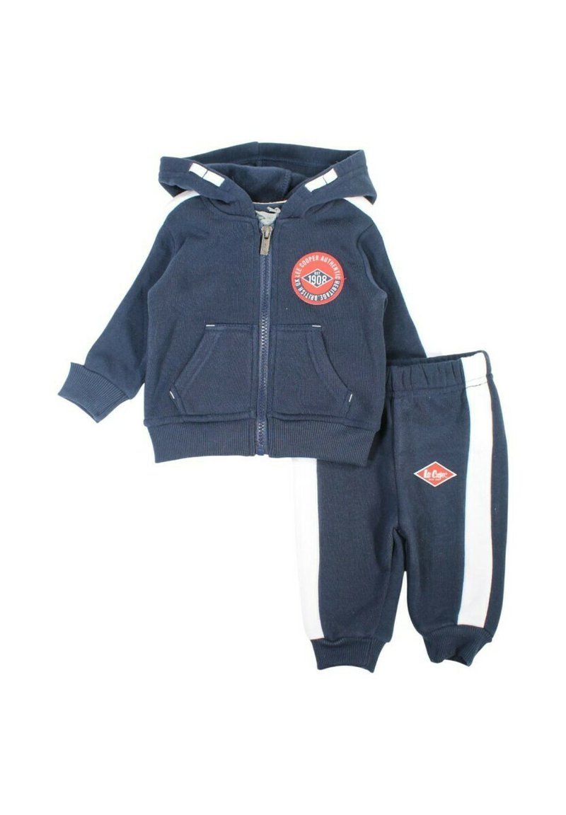 Survêtement pour tout-petit bleu marine comprenant un sweat à capuche zippé avec poches avant et un écusson logo, assorti à un pantalon avec des bandes blanches sur les côtés.