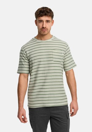 Mand iført grøn og hvidstribet kortærmet skjorte med brystlomme og mørkegrå cargobukser, stående mod en ensfarvet baggrund.