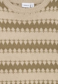 Maglione a maniche corte in beige con motivi geometrici verde oliva. Collo a girocollo a coste e texture morbida. Etichetta visibile.