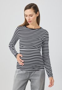 Black and white striped long-sleeve shirt with a round neckline, made of soft fabric, paired with gray trousers. Smooth texture, no notable accents.