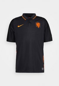 Polo nero realizzato in tessuto traspirante. Presenta dettagli e strisce arancioni sul collo. Mostra un emblema di leone e il logo Nike.