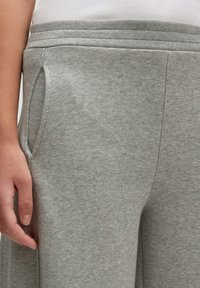 Grijze katoenen sweatpants hebben een elastische tailleband en zijzakken, met een gladde textuur en een relaxte pasvorm.