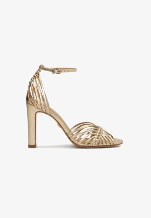 Sandale aurii cu toc înalt, cu curele împletite, vârful deschis și cataramă la gleznă. Finisaj metalic neted, cu detalii pe curele verticale și diagonale.