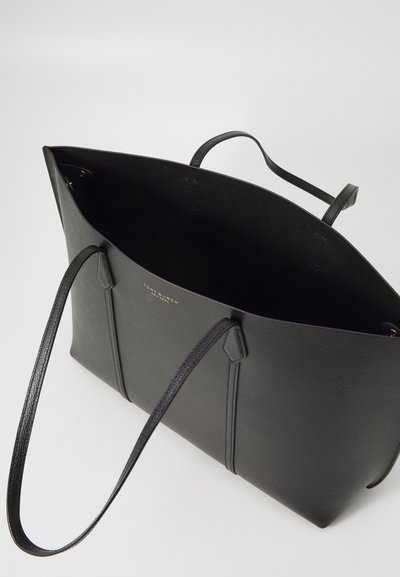 Sac fourre-tout en cuir noir avec deux anses, forme structurée, surface texturée et logo doré à l'intérieur. Ouverture en haut sans fermeture.