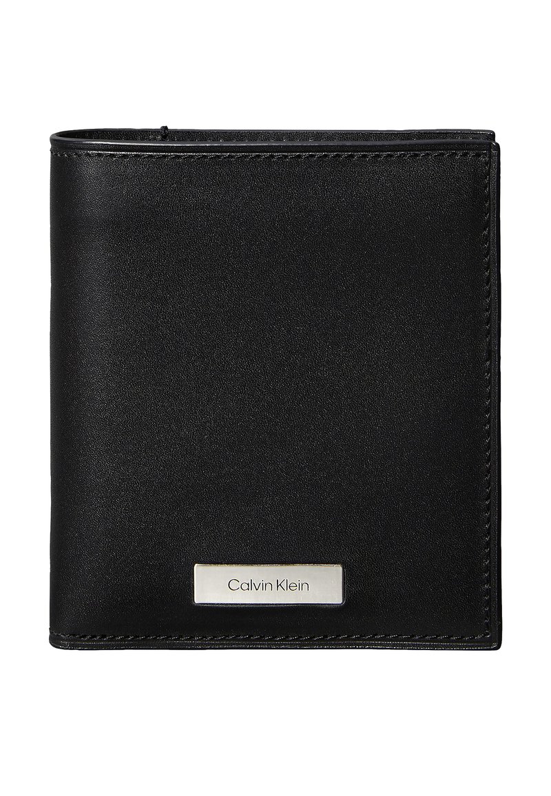 Czarny skórzany portfel o gładkiej fakturze i obszytych krawędziach. Na przedniej stronie znajduje się srebrna plakietka z logo Calvin Klein. Kompaktowy, prostokątny design.