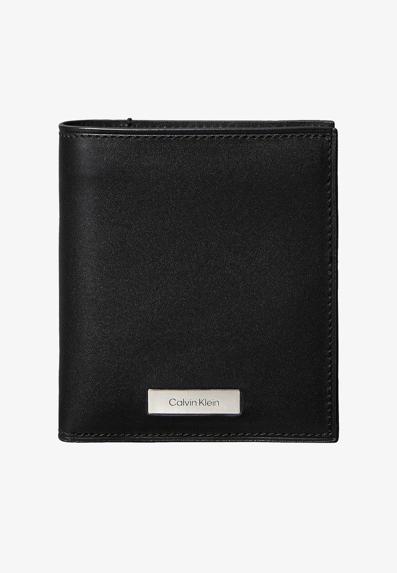 Czarny skórzany portfel o gładkiej fakturze i obszytych krawędziach. Na przedniej stronie znajduje się srebrna plakietka z logo Calvin Klein. Kompaktowy, prostokątny design.