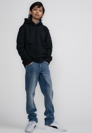 Zwarte hoodie met kangoeroezak, blauwe jeans en witte sneakers met zwarte accenten. Casual pasvorm ontworpen voor comfort.