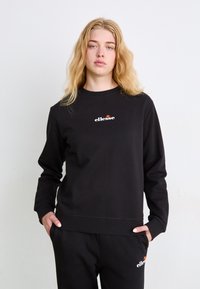 Sudadera negra de manga larga, con puños acanalados y escote redondeado. Presenta un logo en blanco y rojo en el pecho. Fabricada con tela suave.