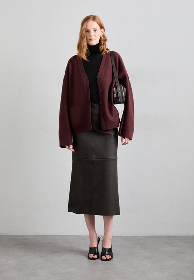 Burgundin iso cardigan, jossa on napit, musta poolopaita, ruskea nahkahuivi midi-hame ja mustat avokkaat. Yksinkertainen olkalaukku korostaa asua.