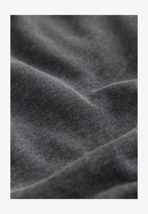Tmavě šedá, měkká tkanina s hladkým povrchem, která má jemné záhyby a vrásky, naznačující splývání a hloubku materiálu.