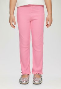 Roze ribbellegging met een aansluitend ontwerp, met ruches aan de zoom. Gecombineerd met metallic zilveren ballet flats.