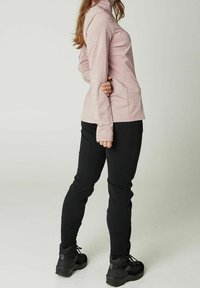 Lyserød langærmet top med høj krave, kombineret med sorte tætsiddende bukser og sorte vandresko. Blødt, tekstureret stof, atletisk pasform.