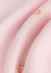 Material roz tricotat cu un model de puncte mici în relief și un design brodat cu rață, prezentând o textură moale și netedă.