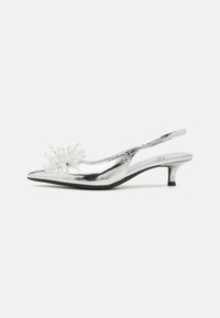 Srebrni slingback čevlji z ostrim nosom, teksturirano kovinsko zaključek in dekorativna prozorna kristalna okrasitev spredaj.