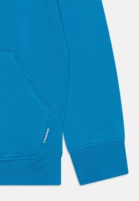 Sudadera de algodón azul con un bolsillo frontal, puños acanalados y una etiqueta en el dobladillo lateral con el nombre de la marca "Vingino". Textura suave y diseño simple.