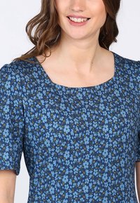 Blaues Blumenmuster-Kleid mit quadratischem Ausschnitt, kurzen Ärmeln und einem strukturierten Stoff mit kleinen hellblauen und grünen Blumenmustern.