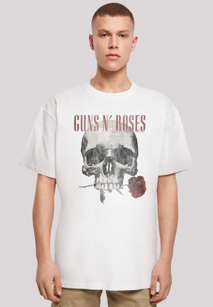 White cotton t-shirt featuring a skull graphic and red rose, with "GUNS N' ROSES" printed above in bold lettering. Loose fit, short sleeves.