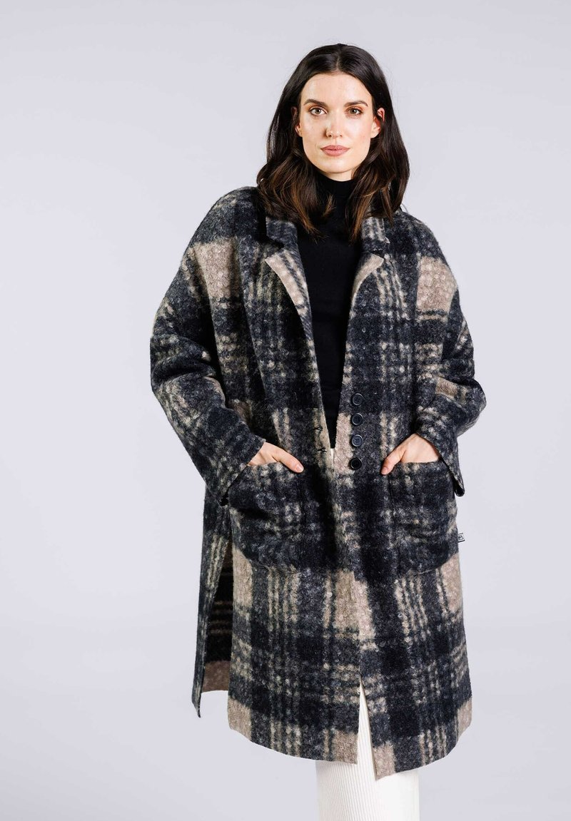 Manteau à carreaux en mélange de laine présentant des tons de bleu, noir et beige, avec un col cranté, de grandes poches et une fermeture à boutons.