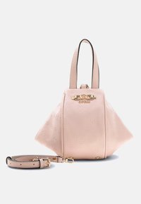 Sac à main Guess rose clair avec motif logo en relief, plaque logo dorée, double poignée et bandoulière amovible sur fond blanc.