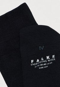 Sosete din lână de culoare bleumarin închis, cu textură ribbed, având informații despre branding și mărime în alb și albastru deschis pe lateral.