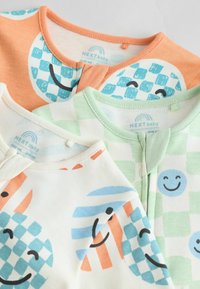 Drei Baby-Oberteile aus weichem Stoff in sanften Farben: Orange, Grün und Creme, mit verspielten Mustern von lächelnden Gesichtern und geometrischen Formen.