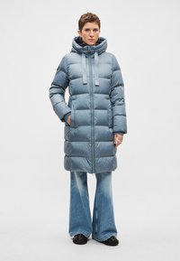 Gewatteerde blauwe donsjas met capuchon, ritssluiting aan de voorkant en twee zijzakken; heeft brede mouwen en een ontwerp tot op de knie.