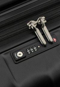 Valigia rigida nera con superficie texture, doppie cerniere, lucchetto combinazione integrato e chiave per ulteriore sicurezza.