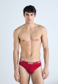 Røde bomuldsbriefs med en hvid og sort elastisk talje med "BOSS" logo. Glat tekstur, tætsiddende pasform, klassisk design.