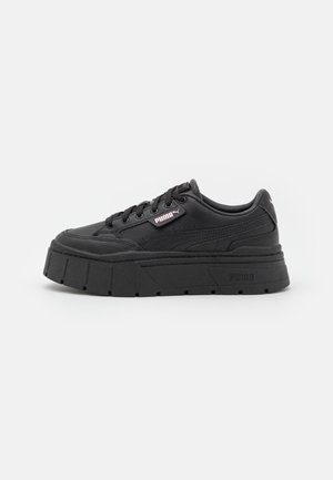 Czarny sneaker na platformie z grubą podeszwą, wiązany z przodu, z metką z logo Puma po boku na białym tle.