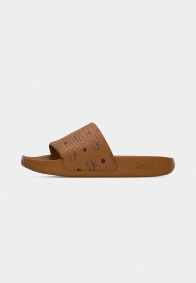 Sandale mule MCM marron avec bande texturée arborant des logos noirs et des diamants, avec un marquage MCM embossé sur le côté de la semelle.