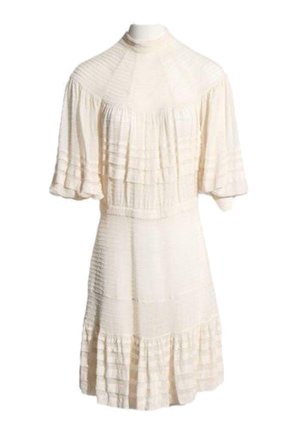 Robe crème mi-longue aux genoux avec col montant, manches courtes ballon et texture plissée horizontale sur toute la surface.