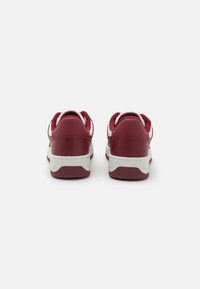 Sarkani ādas sporta apavi ar baltiem akcentiem, noapaļota forma, gumijas zoles un mīksti apkakles. Iezīmējas ar kontrastējošām šuvju detaļām.