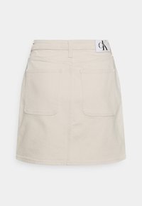Beige farkkua skirt, jossa on suora leikkaus, takataskut ja merkkilabel vyötäröllä. Sileä pinta ja ommellut yksityiskohdat koko matkalta.