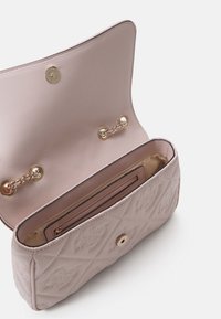 Sac épaule matelassé rose pâle avec bandoulière chaîne, rabat ouvert et poche intérieure zippée sur doublure beige.
