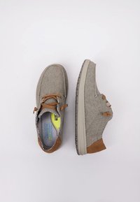 Zapatos de lona grises con acentos de cuero marrón, punta redonda y suela contrastante. Presentan cordones y un acabado texturizado. Diseño ligero.