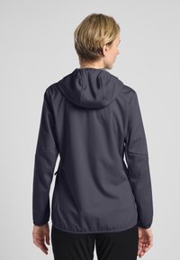Giacca a cappuccio grigia con una texture liscia, design aderente e spalle senza cuciture. Presenta un cappuccio con cordoncino e polsini elasticizzati.