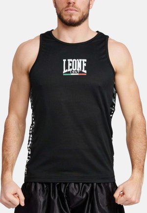Uomo che indossa una canotta sportiva nera senza maniche con il logo "LEONE 1947" e pantaloncini sportivi neri, in piedi con i pugni chiusi.