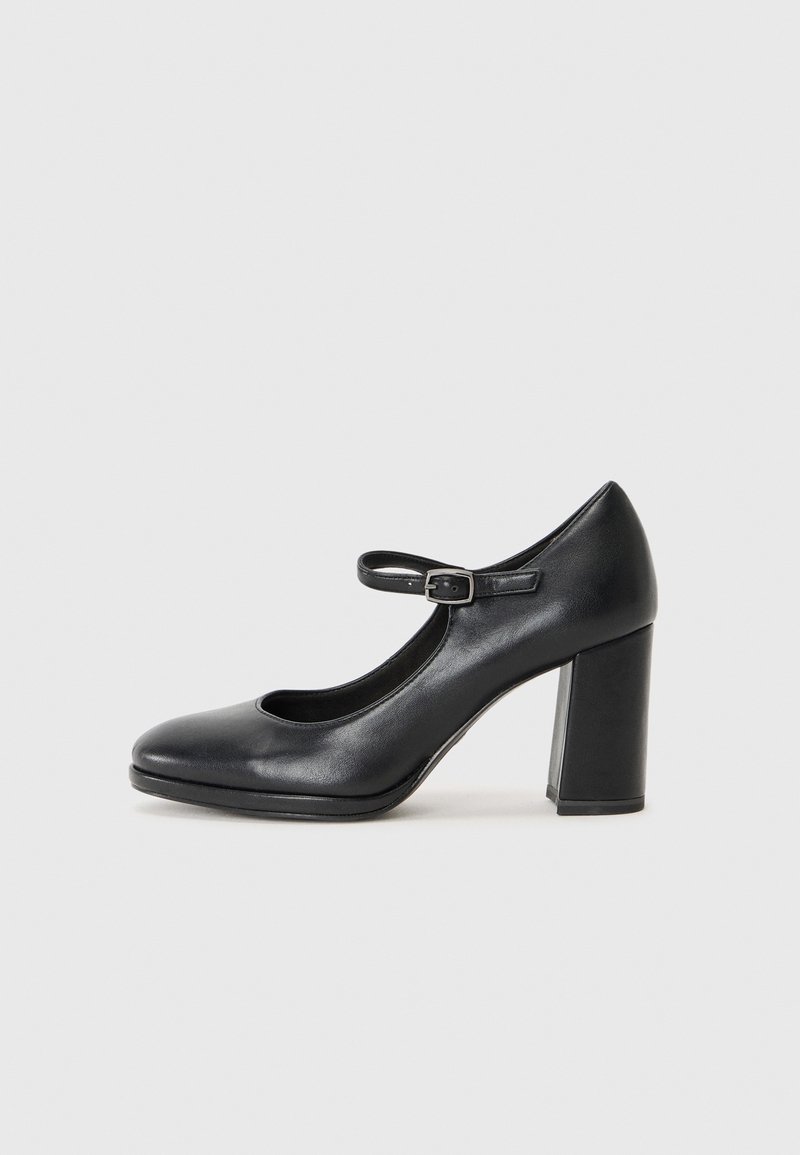 Escarpin Mary Jane en cuir noir avec bout arrondi, bride à la cheville et talon carré épais. Texture lisse, design minimaliste, sans motifs apparents.