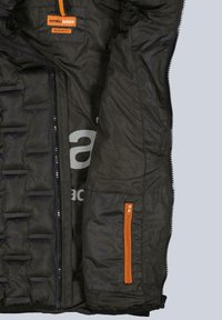 Schwarze gesteppte Steppjacke mit einem orangen Reißverschlusstasche und einem orangen Etikett. Gepolstertes Innenfutter mit grauem Markenlogo. Normaler Schnitt.